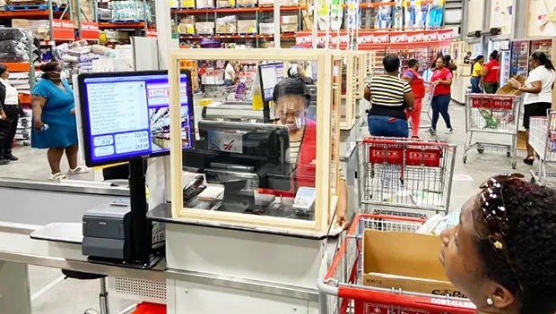 Cost-U-Less checker behind a plexiglass shield.