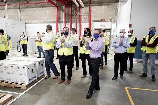 Pfizer employees clap after line workers finished packing boxes of vaccine
