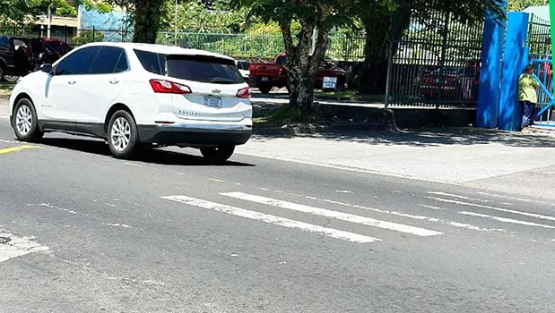 Car passes crosswalk with faded paint