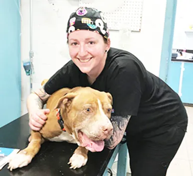 Dr. Kathleen Riley with her patient, a large bown and white dog named ‘KAMA’