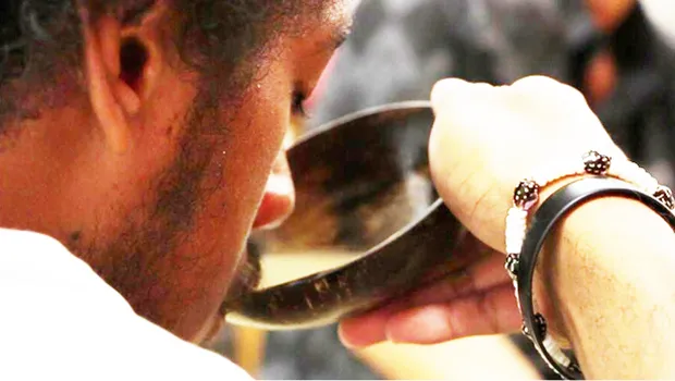 Man takes a sip of kava from the bowl.
