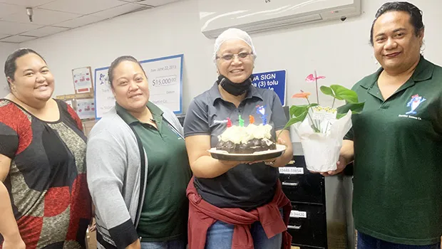 Molly Schuster holding her birthday cake with co-workers