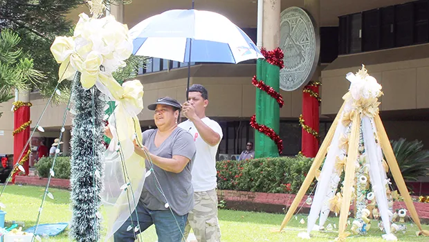 Two ASG employees hang Christmas lights at the EOB