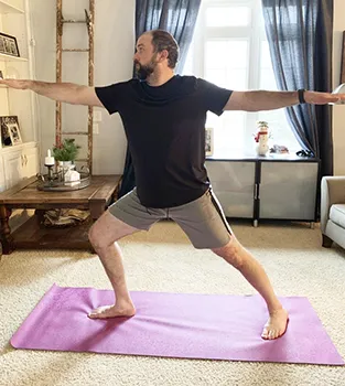 In this March 19, 2020, photo made available by Steve Latart, Latard does yoga exercises at his home in Rogers, Minn.