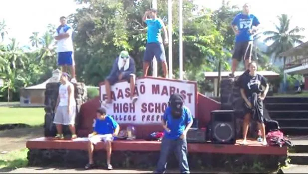 Fa’asao Marist High School sign with students standing near