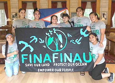 Finafinau members with sign saying save our land, protect our ocean, empower our people