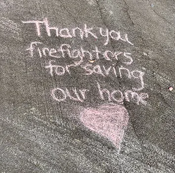thank you message chalked on the driveway of a home that was spared.