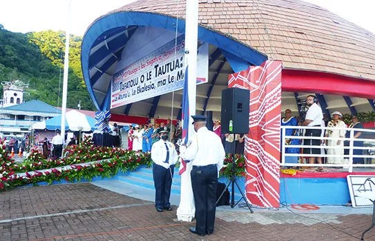 Police officers prepare to raise flags while VIPs watch from the background.