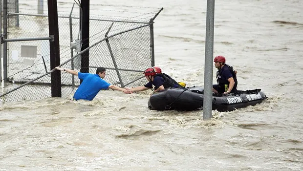 Rescue personnel grab the the hand of a man stranded in rushing water