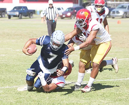 Samoana Sharks quarterback Viliamu Tanielu is brought down by three Tafuna Warrior defenders