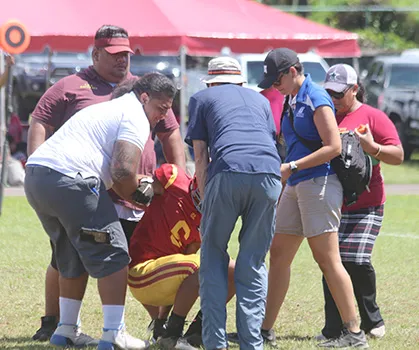 ASHSAA ATC Florence Wasko and Dr. Edwards helping Tafuna Warriors wide receiver Isaiah Gurr