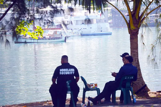 Homeland security personnel siting on shore in sight of yacht