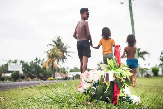 Village children walk past a cross planted at Faleula 