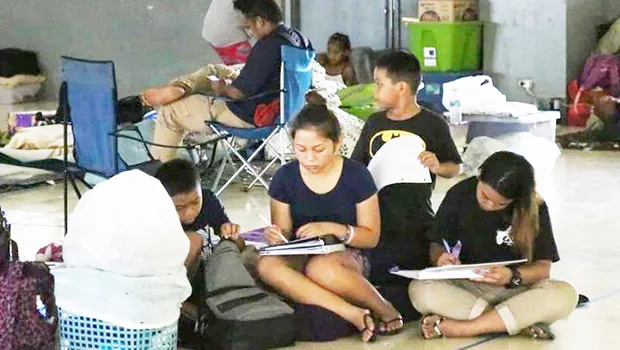  Young students do school work to pass the time while seeking shelter Monday at Astumbo Elementary School.