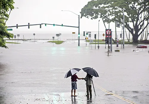People stand near flood waters from Hurricane Lane in Hilo, Hawaii. 