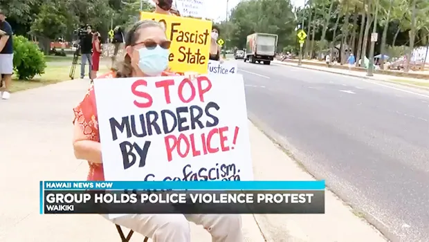 Demonstrators with signs in Waikiki waving to traffic
