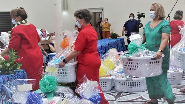 Three female staff members carrying gift baskets into Hope House