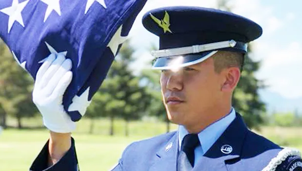 Senior Airman Darias Faaita preparing to present an American Flag to its recipient.