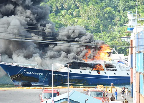 The Jeanette on fire and being towed out of the harbor