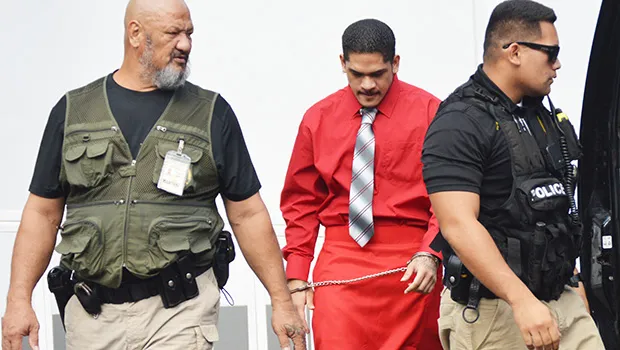 Manu Lefatia in handcuffs escorted by two police officers