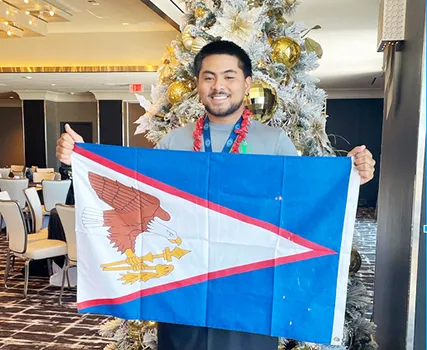 Mataio Suluai carrying the American Samoan flag