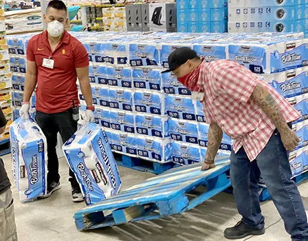 Two store employees stocking toliet paper