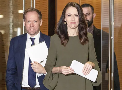 New Zealand Prime Minister Jacinda Ardern with two men in the background