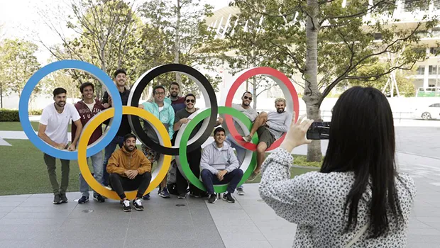 A group of students from Uruguay pose for a souvenir picture on the Olympic Rings set outside the Olympic Stadium in Tokyo