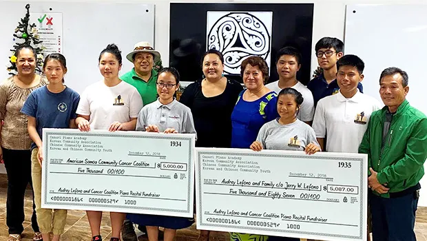 Students of Onnuri Piano Academy — together with members of American Samoa's Korean and Chinese Associations, and the Korean and Chinese Community Youth Groups — pictured with two checks