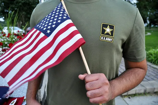 a Pakistani recruit, 22, who was recently discharged from the U.S. Army, holds an American flag as he poses for a picture. The man asked his name and location to be undisclosed for safety reasons. The AP interviewed three recruits from Brazil, Pakistan and Iran, all of whom said they were devastated by their unexpected discharges