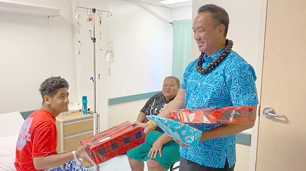 A young man named Troy receives a gift from Paul Young on behalf of Rotary Club of Pago Pago