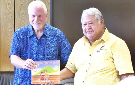 Samoan PM Tuilaepa Sailele receiving a textbook from Applied Scholastics ambassador Warren Meyer