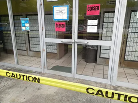 Post Office front door with closed signs and caution tape