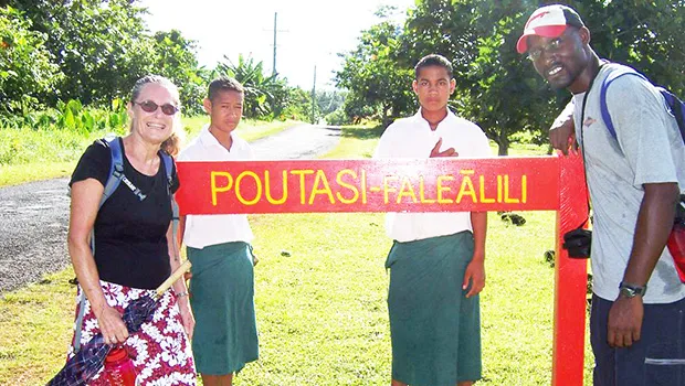 Peace Corps volunteers infron of Poutasi Village sign 