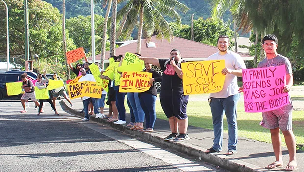 A group of about 15 peaceful protesters on the sidewalk in front of Utulei Beach