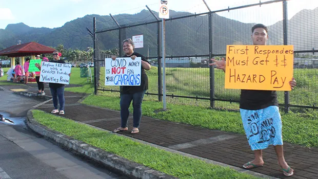 Three protesters with signs protesting governer's checks to fono