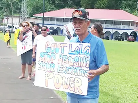 Pago Pago High Chief Pulu Ae Ae Jr. holds up a sign that reads: “Gov. Lolo: Stop abusing your executive power"