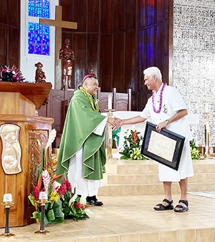 shows Tualauta Faipule Larry S. Sanitoa (right) shaking hands with Bishop Kolio Etuale Tumanuvao,