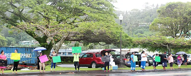 A group of residents - some with umbrellas - participating  in the “Wave for repatriation flights - Not open borders”