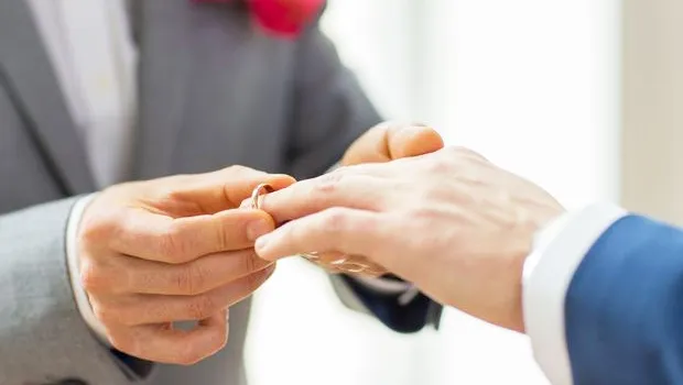 Hands of two men exchanging rings