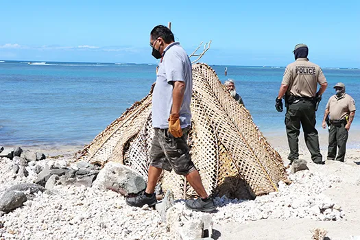 Saute Sapolu looking out from behind his fale as Honolulu cops dismantle it.