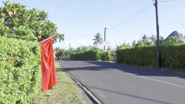 Empty street in Apia with red flag outside a yard.