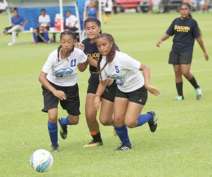 Two Samoana players defend against a Fa’asao-Marist opponent 