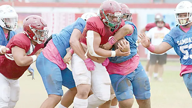 Tafuna High School’s powerback is gang-tackled by three Samoana defenders 