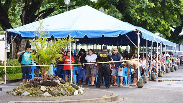 Large crowd under tents in the parking lot of the Territorial Bank of American Samoa