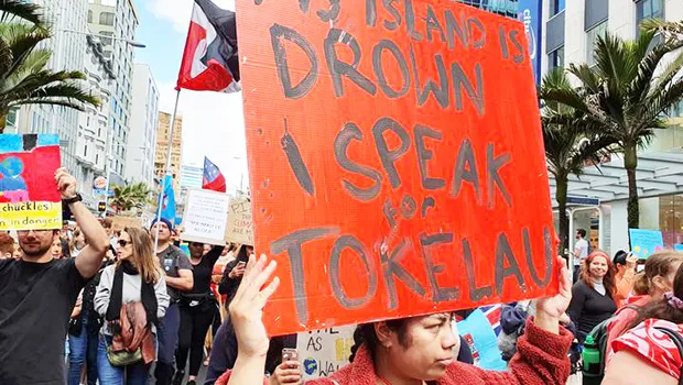 A Tokelaun woman marching for climate action with a sign
