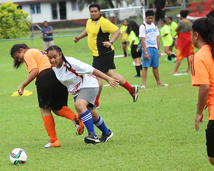A Vaiala Tongan player dribbles by an Utulei Youth defender 