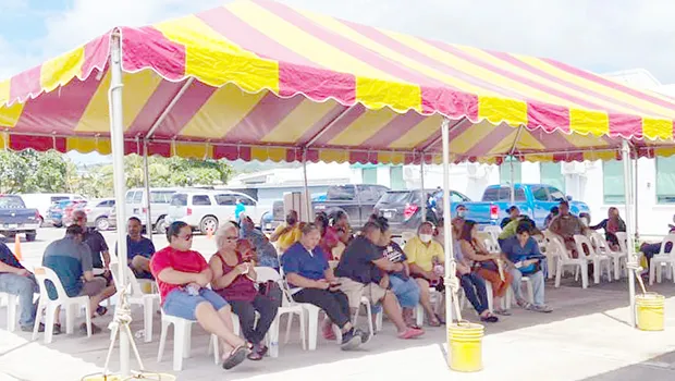 Individuals waiting to get their COVID-19 vaccine under a tent next to the DoH quarantine facility in Tafuna