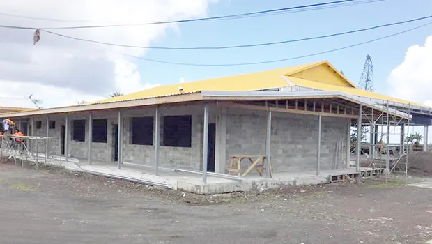 Gym and adjoining building in progress with two workmen on roof