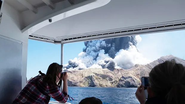 Tourists on a boat look at the eruption of the volcano